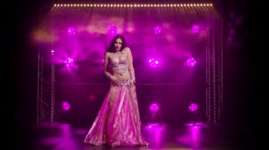 Güzel oryantal dansçı dans ediyor ve vücudunun esnekliğini ve çekiciliğini gösteriyor. Dumanda mor arkaplan.