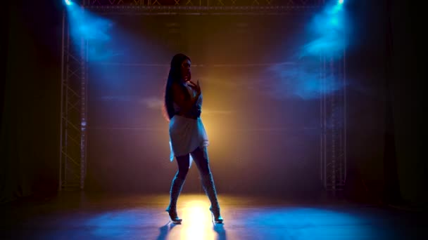 Karcsú magas lány görög görögök Goddes ruha és koszorú magas divat bemutatja a rugalmasság és a szexualitás a test a tánc. Silhouette egy sötét háttér kék neon fények. — Stock videók