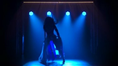 İngiliz bayrağı ve yapay elmasları renginde seksi bir takım elbiseyle dans eden siluet gibi ince bir kadın. Duman ve mavi neon ışıklarla karanlık stüdyoda çekildi. Yavaş çekim.