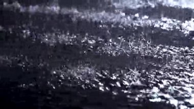 Su yüzeyine yakın bir ışık parıltısıyla püskürt. Siyah arka plan, stüdyo.