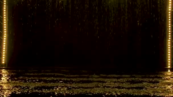 Gele spatten regen vallen tegen de achtergrond van een podium verlichting in donkere studio. Langzame beweging. — Stockvideo