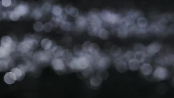 Fundo borrado preto ondulação água brilhante, bokeh. Movimento lento. Fechar. — Vídeo de Stock