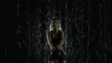 Crossfit kettlebell egzersizi. Stüdyoda yağmurun altında spor yapan kadın antrenman yapıyor. Güç eğitimi. Ağır çekim. Kapat..