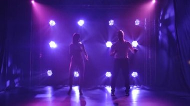 Dans eden genç çift Latin müziği. Bachata, merengue, salsa. Arka planda neon ışıkları olan karanlık bir stüdyoda çekilmiş..