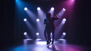 Dans eden genç çift Latin müziği. Bachata, merengue, salsa. Arka planda neon ışıkları olan karanlık bir stüdyoda çekilmiş..