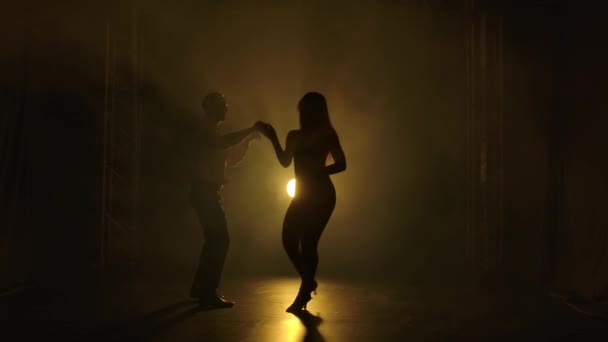 Pasangan muda menari musik latin. Bachata, merengue, salsa. Shot in a dark studio with neon lights in the background. — Stok Video