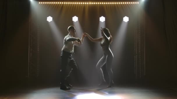 Молода пара танцює латинську музику. Бачата, меренг, сальса. Знімок у темній студії з неоновими вогнями на задньому плані . — стокове відео