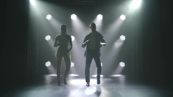 Mladý pár tančí latinskou hudbu. Bachata, merengue, salsa. Natočeno v tmavém studiu s neonovými světly v pozadí. — Stock video