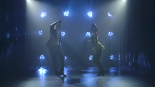 Dans eden genç çift Latin müziği. Bachata, merengue, salsa. Arka planda neon ışıkları olan karanlık bir stüdyoda çekilmiş.. — Stok video