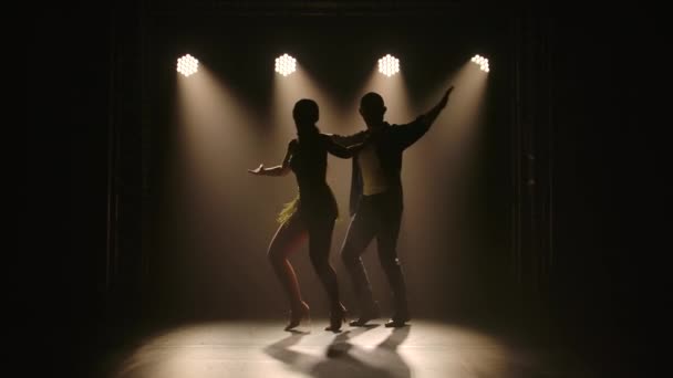 Latin zenét táncoló fiatal pár. Bachata, merengue, salsa. Lelőtték egy sötét stúdióban neon fények a háttérben. — Stock videók