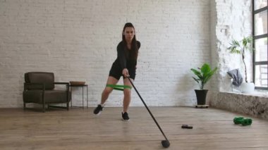 Bir kadın hokey koçu spor lastiği kullanarak hokey sopasıyla kayma hareketleri yapıyor. Yavaş çekim.