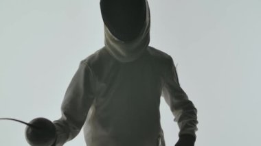 Kılıç ustası kılıç kullanarak bazı basit hareketleri gösteriyor. Beyaz arka planda izole edilmiş bir çekim. Ağır çekim. Kapat..