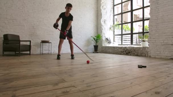 Un jeune garçon joue au hockey par terre dans la pièce. Mouvement lent. — Video