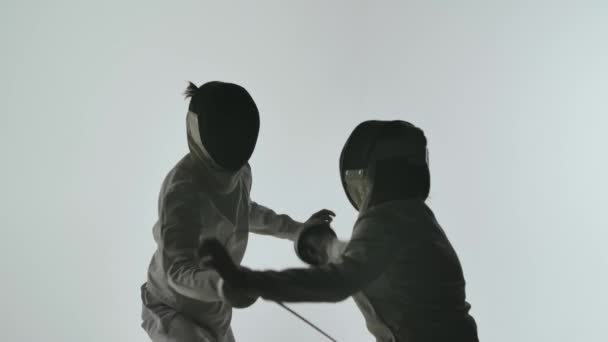Поединок двух фехтовальщиков на белом фоне в студии. Два профессиональных фехтовальщика демонстрируют мастерство фехтования в их схватке на фольге. Медленное движение. Закрыть. — стоковое видео