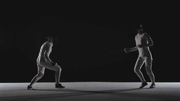 Beyaz takım elbiseli iki kılıç ustasının siluetleri. Folyo eskrim ustası. Spor yaşam tarzı konsepti. Stüdyo ışıklarıyla içeride çekilmiş. Yavaş çekim. — Stok video