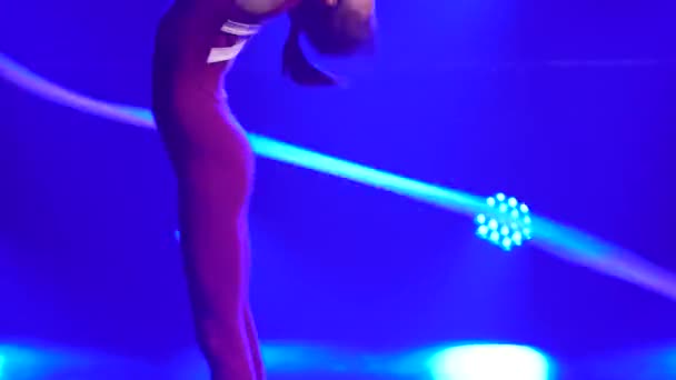 Ritmische gymnastiek. Een jong atletisch meisje doet een oefening met een tape. Neergeschoten in een donkere studio met paarse neonverlichting op de achtergrond. Sluiten.. — Stockvideo