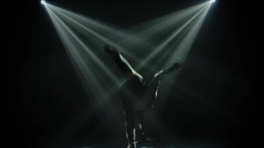 Sokak dansı tarzında dans eden esmer siluetli adam. Siyah arka plan, neon ışıkları ve bir sürü duman. Yavaş çekim.