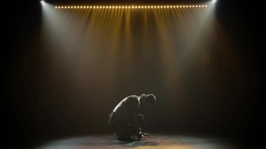 Eşofmanlı genç yakışıklı adam güçlü bir şekilde break dans yapıyor serbest stil, sokak dansı, karmaşık hareketler yapıyor, izole edilmiş, yavaş çekim. Siluet.