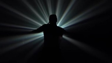 Sokak arası dans ve kalça dansı tarzında hareket eden bir adamın siyah siluetinin alt görüntüsü. Aktif yaşam tarzı konsepti. Yavaş çekim.