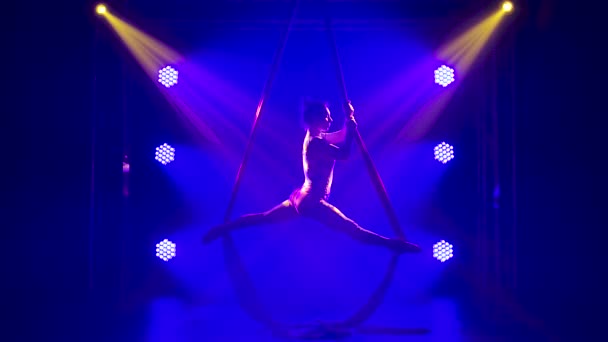 Prachtig silhouet van vrouwelijke gymnaste die in een studio een luchtacrobatisch touw op zijde opvoert. Performance in een donkere studio met blauwe verlichting. Langzame beweging. — Stockvideo