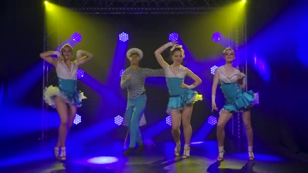 Guy en drie vrouwen in matrozenpakken dansen brandend. Theatrale dansshow. Blauwe neon verlichting op een zwarte achtergrond in de studio. Langzame beweging. — Stockvideo