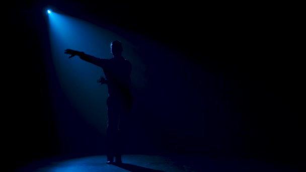 Танцор бальных танцев изящно двигается на сцене. Темный силуэт в синем неоновом свете. Медленное движение. — стоковое видео