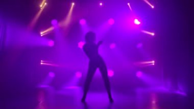 Latin dansı yapan bir kadın. Bachata, merengue, salsa. Arka planda neon ışıkları olan karanlık bir stüdyoda çekilmiş..