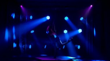 Egzotik striptizci bir gece kulübünde gösteri yapıyor. Zayıf, çekici bir kadın, çok renkli neon ışıkların altında siluete bürünür. Yavaş çekim.