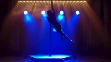 Polonyalı dansçı kadın eğitimi. Güzel genç bir kadın direk dansı yapıyor. Kadın dansçı silueti, fitness ve spor konseptleri. Mavi neon arkaplan.