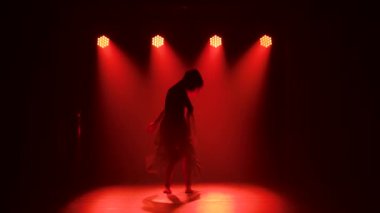 Kulüpte tek başına dans eden modaya uygun genç bir kadın, neon ışığı, bir sürü duman. Moda sokak kıyafeti. Siluet