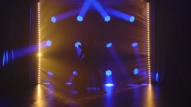 Kulüpte tek başına dans eden modaya uygun genç bir kadın, neon ışığı, bir sürü duman. Moda sokak kıyafeti. Siluet