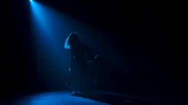 Kulüpte tek başına dans eden modaya uygun genç bir kadın, neon ışığı, bir sürü duman. Moda sokak kıyafeti. Siluet