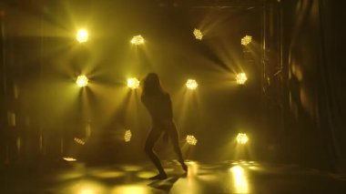 Kulüpte tek başına dans eden modaya uygun genç bir kadın, neon ışığı, bir sürü duman. Moda sokak kıyafeti. Siluet