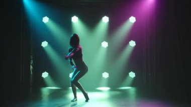 Kulüpte tek başına dans eden modaya uygun genç bir kadın, neon ışığı, bir sürü duman. Moda sokak kıyafeti. Siluet