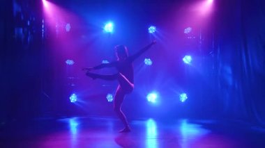 Spot ışıklarıyla modern dans eden bir kadın. Vogue ya da modern dans. Genç dansçı karanlık sahnede oynuyor..