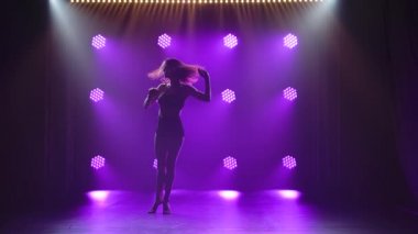 Spot ışıklarıyla modern dans eden bir kadın. Vogue ya da modern dans. Genç dansçı karanlık sahnede oynuyor..