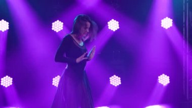 Spot ışıklarıyla modern dans eden bir kadın. Vogue ya da modern dans. Genç dansçı karanlık sahnede oynuyor..