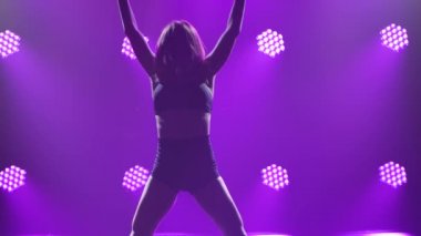 Spot ışıklarıyla modern dans eden bir kadın. Vogue ya da modern dans. Genç dansçı karanlık sahnede oynuyor..