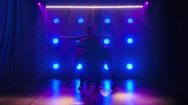 Un grupo de gimnastas masculinos realizan acrobacias. Filmado en el estudio con proyectores azules en el fondo. Movimiento lento. — Vídeos de Stock