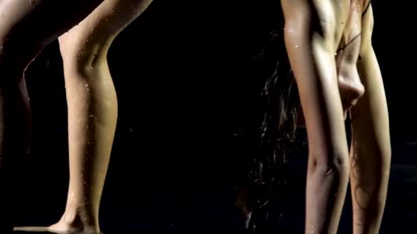 Ευέλικτη γυναίκα γιόγκα άσκηση ένα πόδι προς τα πάνω πόζα απολαμβάνοντας υγιεινό τρόπο ζωής. Το εύκαμπτο σώμα είναι βρεγμένο με νερό. Μαύρο φόντο. Κλείσε.. — Αρχείο Βίντεο