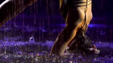 Sportif kadın stüdyo mavi ışığı ve su yağmuru ile ileri tribünde duruyor. Damlalar içinde bir kadın cesedi. Resim stüdyoda siyah bir arkaplanda çekildi. Kapat..