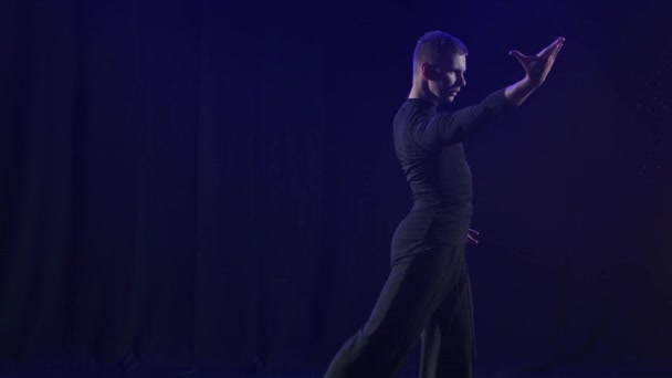 Silueta de una bailarina interpretando un elemento de baile de bachata. Fondo negro con proyectores de neón azul. En cámara lenta. De cerca.. — Vídeos de Stock
