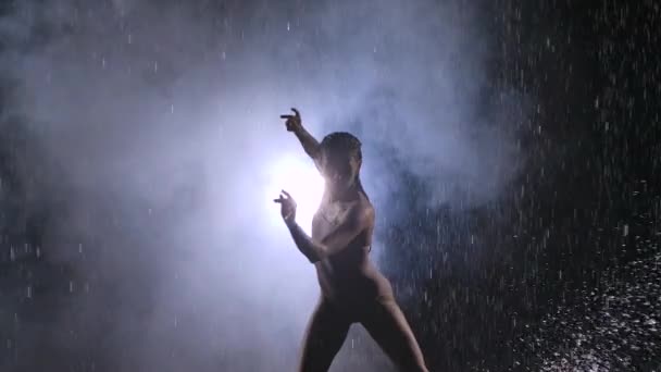 Dansatoare umedă de sex feminin sau balerină în costum de baie bej efectuează dans contemporan pe podea în ploaie și stropi de apă. Silueta. Mişcare lentă. Close up . — Videoclip de stoc