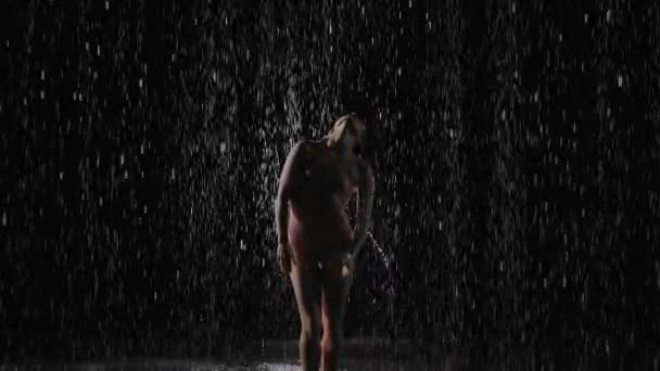 Bailarina femenina realiza danza contemporánea bajo las gotas de lluvia de agua. La bailarina mojada se mueve elegantemente en el estudio bajo el agua de lluvia. En cámara lenta. De cerca.. — Vídeos de Stock