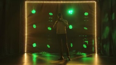 Dinamik renkli ışıkları olan bir caz trompetçisi karanlık stüdyoda trompetini çalar. Siluet. Yavaş çekim.