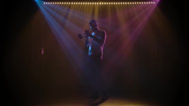 Sahnenin karanlık sahnesinde caz trompeti gösterisi. Siluet. Yavaş çekim.