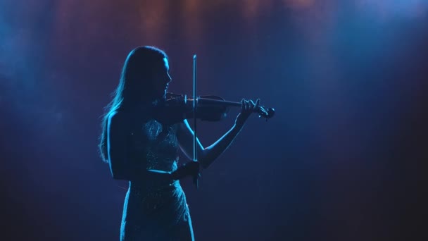 Instrumental solo performance of a classical live melody on a violin. A young girl violinist is silhouetted. Slow motion. Close up. — Stock Video