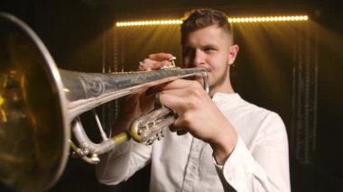 Trompet çalan trompetçi eller yakından müzik aleti çalıyor. Oyuncuların parmakları trompette. Yavaş çekim.