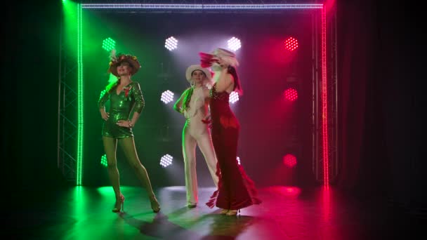 Espectáculo teatral de tres hermosas bailarinas. Las mujeres jóvenes posan en trajes en los colores de la bandera italiana sobre el telón de fondo de focos brillantes. Movimiento lento. — Vídeo de stock