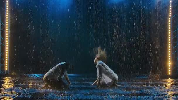 Two beautiful women erotically move on the surface of the water in the rain, creating many splashes. Slow motion. — Stock Video